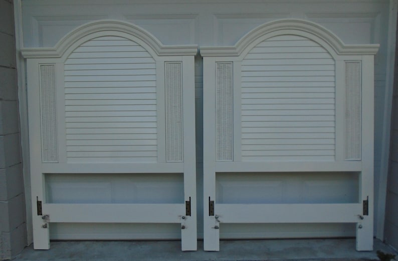 May include: Two white headboards with arched tops and horizontal slat detailing. Each headboard has a rectangular center section with horizontal slats and vertical decorative panels. The headboards are made of wood and have a classic design.