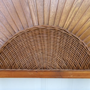 May include: A wooden headboard with a woven rattan half-circle design. The headboard features a sunburst pattern carved into the wood, with a natural finish. The rattan is a warm brown color, adding a touch of texture and visual interest.