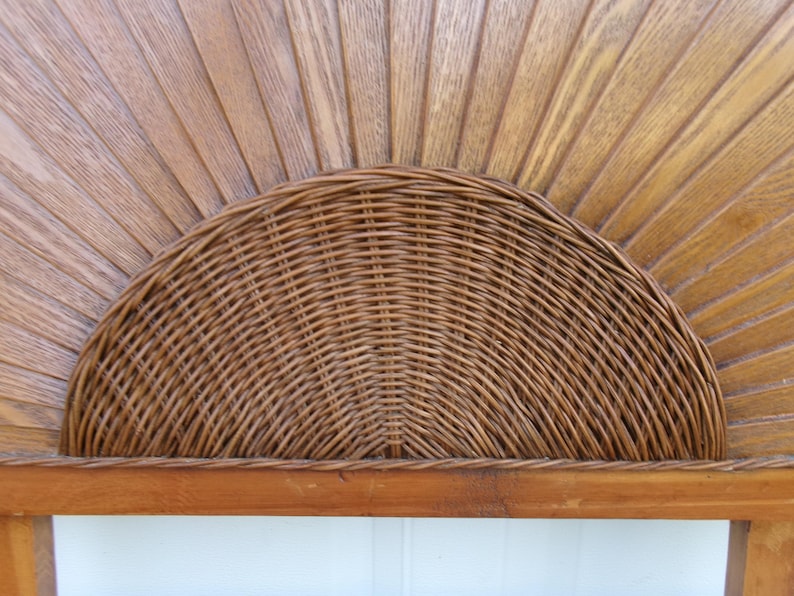 May include: A wooden headboard with a woven rattan half-circle design. The headboard features a sunburst pattern carved into the wood, with a natural finish. The rattan is a warm brown color, adding a touch of texture and visual interest.