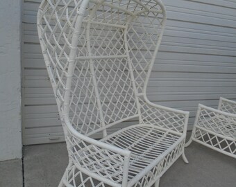 May include: White wicker hooded chair with a woven design. The chair has a high back and a wide seat. The chair is made of natural materials and has a rustic look.