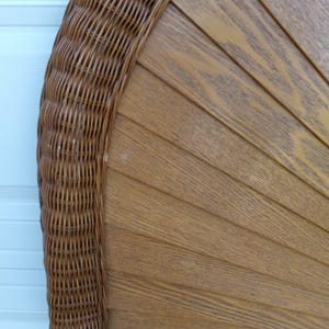 May include: A brown wicker and wood headboard with a fan-like design. The headboard features a woven wicker border and a series of wooden slats arranged in a semi-circular pattern. The wood has a natural grain and a warm, light brown color.