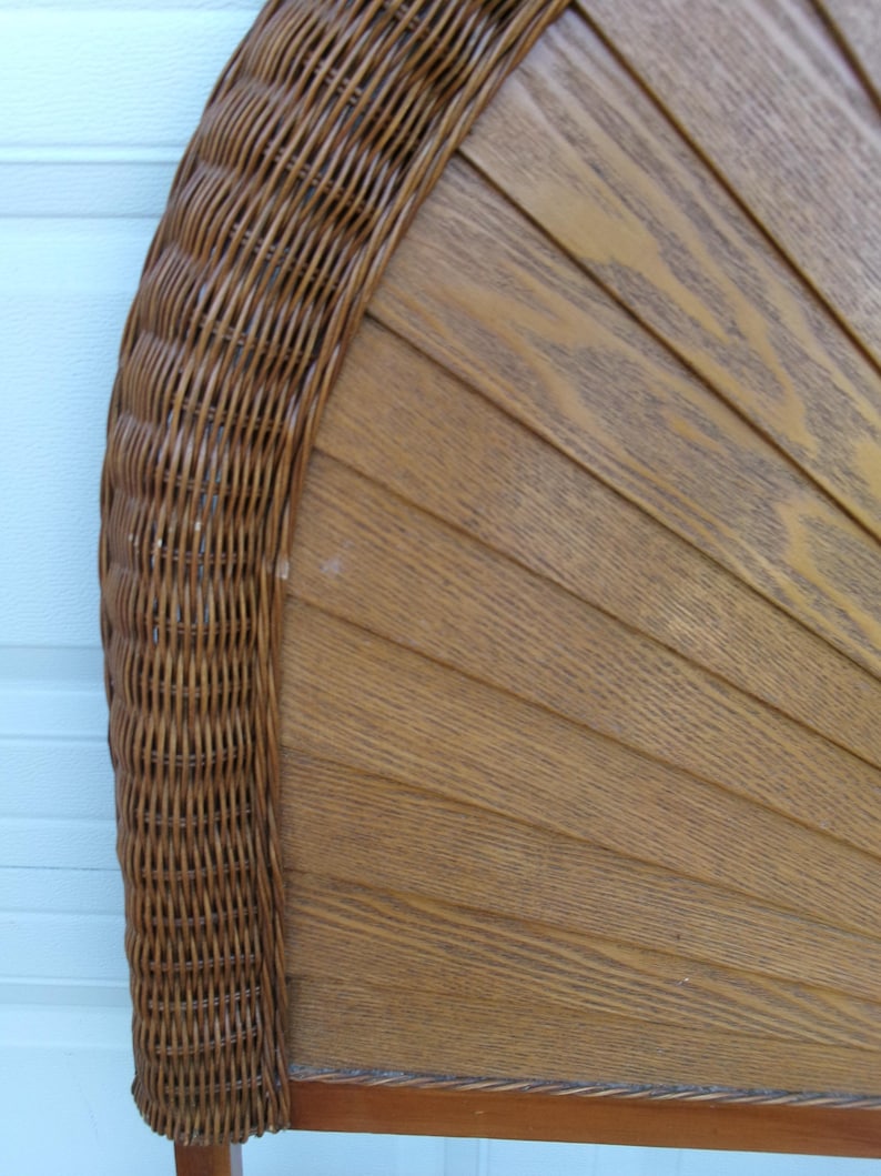 May include: A brown wicker and wood headboard with a fan-like design. The headboard features a woven wicker border and a series of wooden slats arranged in a semi-circular pattern. The wood has a natural grain and a warm, light brown color.