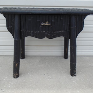 May include: Black wooden end table with a single drawer and four legs. The table is made of woven bamboo and has a distressed finish.