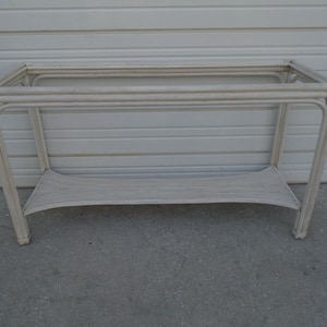 May include: White wicker console table with a single shelf. The table has a simple, rectangular design and is made of woven wicker.