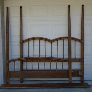 May include: A wooden bed frame with a headboard and footboard. The headboard has a curved top and a slatted design. The footboard is a solid piece of wood. The frame is made of dark brown wood.