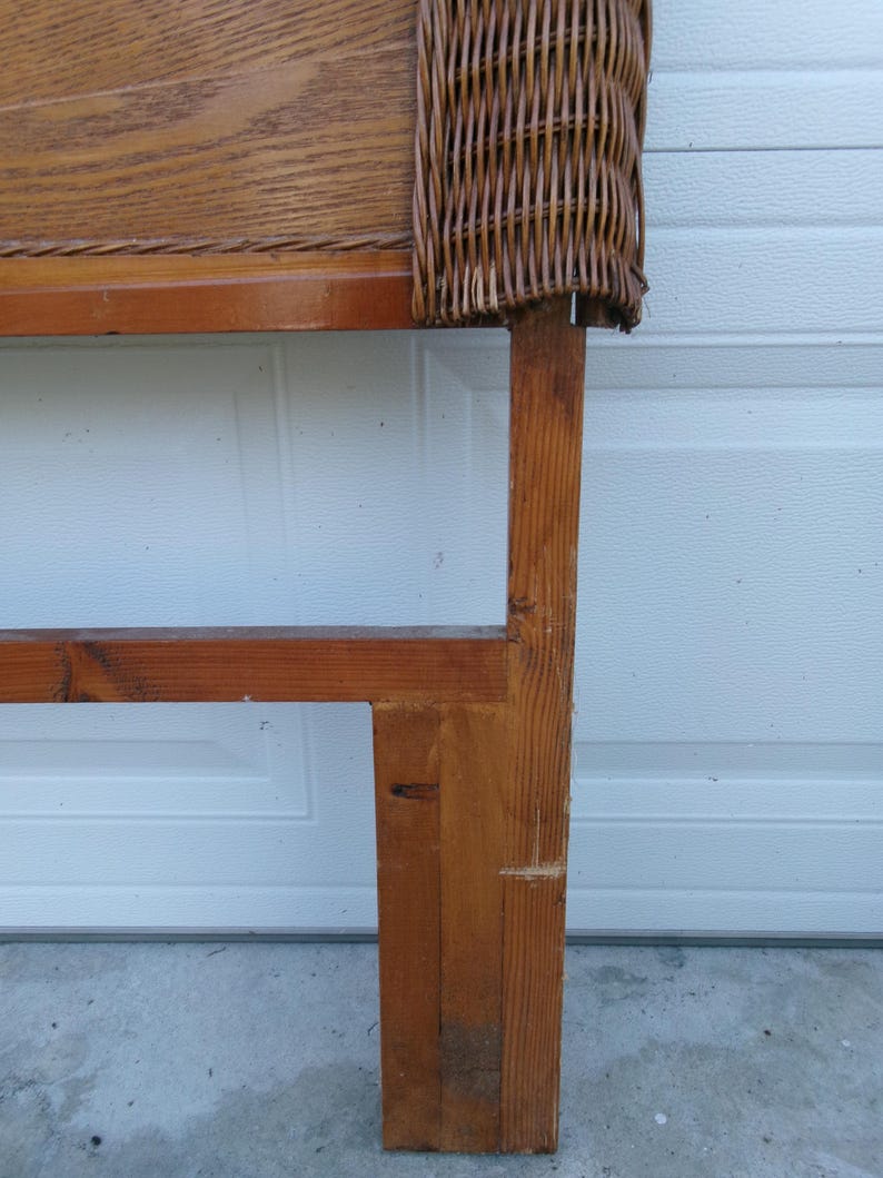 May include: A wooden headboard with a woven wicker top section. The headboard is constructed from light brown wood with a rectangular frame and a woven wicker panel. The wood has visible grain and knots.