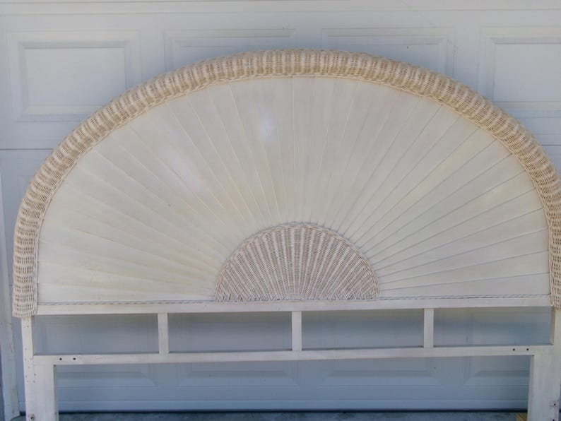 May include: A white and beige fan-shaped headboard with a woven rattan border. The headboard has a rectangular base with a shelf. The design features a sunburst pattern, adding a touch of elegance to bedroom decor.