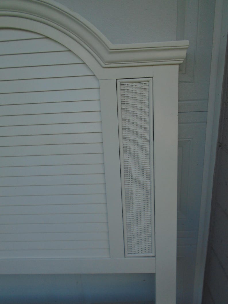 May include: A white headboard with a curved top and a rectangular woven panel. The headboard has horizontal slats and a decorative frame. The overall design is clean and coastal.