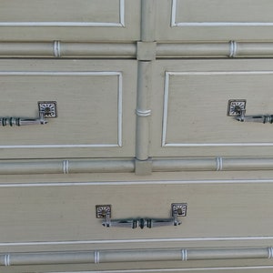 May include: A light green dresser with faux bamboo detailing and silver drawer pulls. The dresser has four drawers.