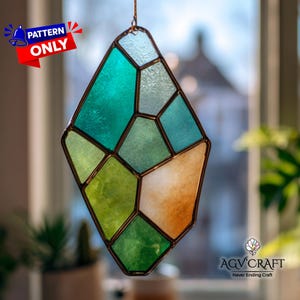 May include: A stained glass suncatcher in a geometric diamond shape, featuring shades of green, blue, and orange. The suncatcher is outlined in a dark metal and is suspended by a thin wire. The text "PATTERN ONLY" is visible in the upper left corner.