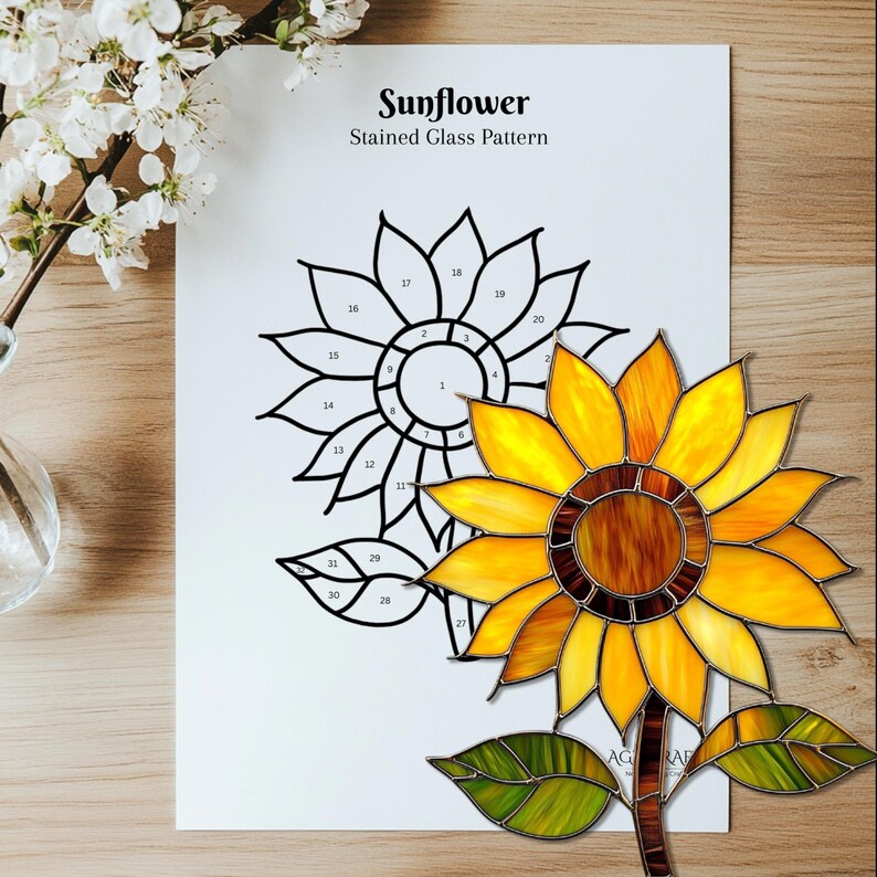 Puede incluir: Un girasol de vidrieras con p&eacute;talos amarillos y marrones, hojas verdes y un tallo marr&oacute;n. Un dibujo lineal en blanco y negro de un girasol est&aacute; sobre un papel blanco con el texto "Sunflower Stained Glass Pattern".