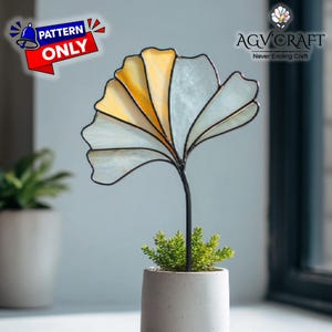 Puede incluir: Un diseño de hoja de ginkgo de vidriera con paneles amarillos y blancos, montado sobre un tallo negro y plantado en una pequeña maceta de hormigón con vegetación. La imagen incluye el texto "PATTERN ONLY".