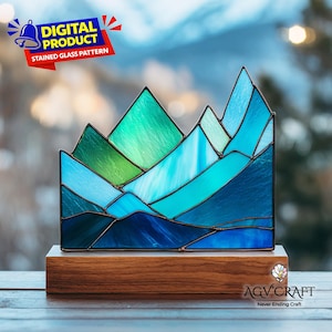 May include: A stained glass mountain range in shades of blue and green, set on a wooden base. The artwork features a geometric design with varying shades of blue and green, creating a landscape effect. The words "DIGITAL PRODUCT STAINED GLASS PATTERN" are in the top left corner.