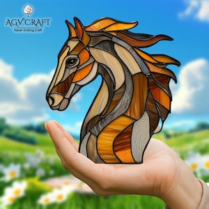 Peut inclure: Une sculpture de t&ecirc;te de cheval en vitrail aux tons bruns, orang&eacute;s et beiges. L'&oelig;uvre est tenue dans une main, avec un arri&egrave;re-plan flou d'un ciel bleu et d'un champ vert. Le logo "AGV CRAFT" est dans le coin sup&eacute;rieur gauche.