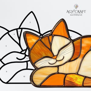 May include: A stained glass cat with orange, yellow, and cream-colored panels, outlined in a dark brown frame. The cat is in a relaxed pose with its eyes closed. A black and white line drawing of the cat's outline is next to the stained glass cat. The logo "AGV Craft" is in the upper right corner.