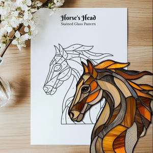 Peut inclure: Un patron de vitrail intitul&eacute; "Horse's Head" pr&eacute;sentant un contour d&eacute;taill&eacute; et un motif termin&eacute;. La t&ecirc;te de cheval finie est r&eacute;alis&eacute;e dans des tons de marron, d'orange et d'ambre. Le motif est sur papier blanc, avec un fond en bois.