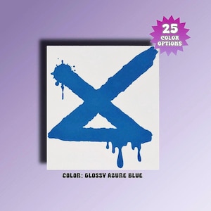 May include: A square white decal featuring a large, bold, azure blue letter X with a spray-paint effect. The design includes paint splatters at the top left and drips at the bottom. A pink starburst graphic in the corner reads 25 COLOR OPTIONS.
