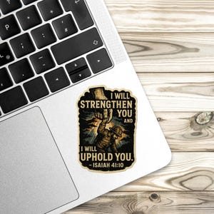 Distressed-style sticker featuring a man in work gear being lifted by a divine hand with the text “I will strengthen you and I will uphold you – Isaiah 41:10” set against a stormy background with rays of light