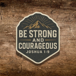 May include: A sticker with a dark gray background and a white border. The sticker features a gold mountain graphic and the words "BE STRONG AND COURAGEOUS" with "JOSHUA 1:9" below.