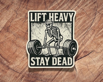 May include: Black and white sticker with a skeleton lifting a barbell. The sticker says "Lift Heavy Stay Dead".