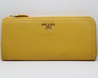 May include: A yellow leather Prada wallet with a gold zipper and logo.