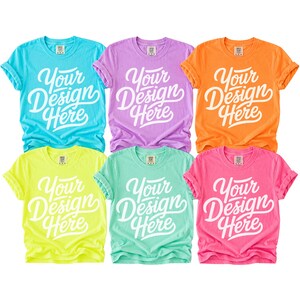May include: Six colorful t-shirts in shades of blue, purple, orange, yellow, green, and pink. Each shirt has the text "Your Design Here" in white script. The shirts are short-sleeved and appear to be made of a soft material.