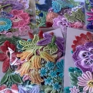 May include: Assortment of colorful lace flower appliques in various sizes and styles. The appliques are packaged in clear plastic bags and feature delicate floral designs.