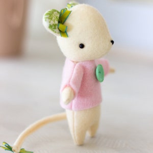 Peut inclure: Une souris en peluche faite &agrave; la main avec un corps cr&egrave;me et un pull rose. La souris a un bouton vert et un n&oelig;ud vert et jaune sur l'oreille. La souris a une longue queue de couleur cr&egrave;me.