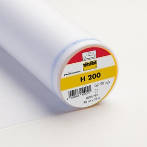 Peut inclure: Un rouleau de tissu d'entoilage blanc, étiqueté "H 200" par Vlieseline. L'étiquette est jaune et rouge, avec du texte indiquant que le tissu mesure 90 cm de large et 25 m de long. Le tissu est 100% PES.