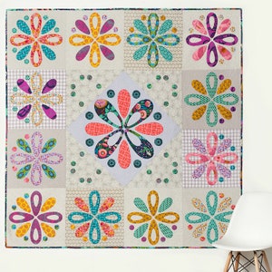 Puede incluir: Una colcha colorida con un diseño de patchwork que presenta un patrón repetitivo de flores estilizadas en tonos de rosa, morado, turquesa, amarillo y naranja. La colcha está hecha de cuadrados y diamantes, y las flores están dispuestas en un patrón simétrico.
