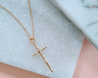 May include: A gold chain necklace with a textured gold cross pendant.