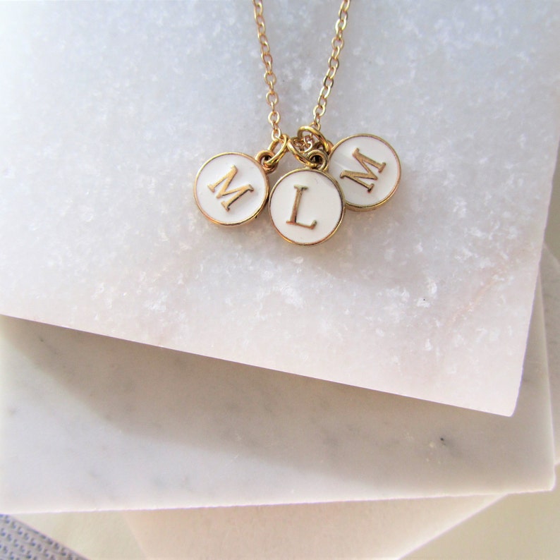 Three round white enamel with a gold letter in the centre of the disc charm with gold around the outside of the charm on  delicate gold chain.  choose your own initials to represent your children or grandchildren