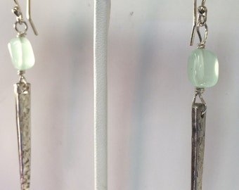 May include: Silver dangle earrings with a light green gemstone and a textured silver spike.