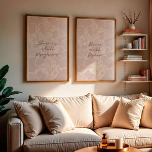 May include: A cozy living room scene featuring a beige sectional sofa with multiple pillows. Two framed art prints with floral patterns and inspirational quotes hang above the sofa. A small side table holds a candle and a tray with a bottle.