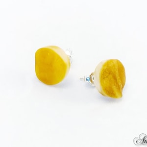 May include: A pair of amber earrings with a yellow and white color scheme. The earrings are made of natural amber and have a unique, organic shape.