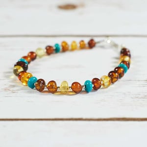 May include: A multi-coloured amber and turquoise beaded bracelet with a silver clasp.