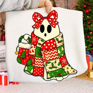 Puede incluir: Ilustración de un fantasma blanco con un lazo rojo de lunares, una colcha de retazos y un calcetín navideño. La colcha presenta patrones rojos, verdes y blancos. El calcetín es rojo con un diseño de árbol de Navidad verde y una estrella dorada.