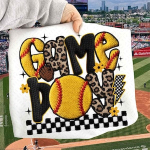 May include: A white softball-themed design with the words "GAME LOVE" in yellow, black, and leopard print. A yellow softball with red stitching is in the center. The design includes a black and white checkered border and yellow flowers.