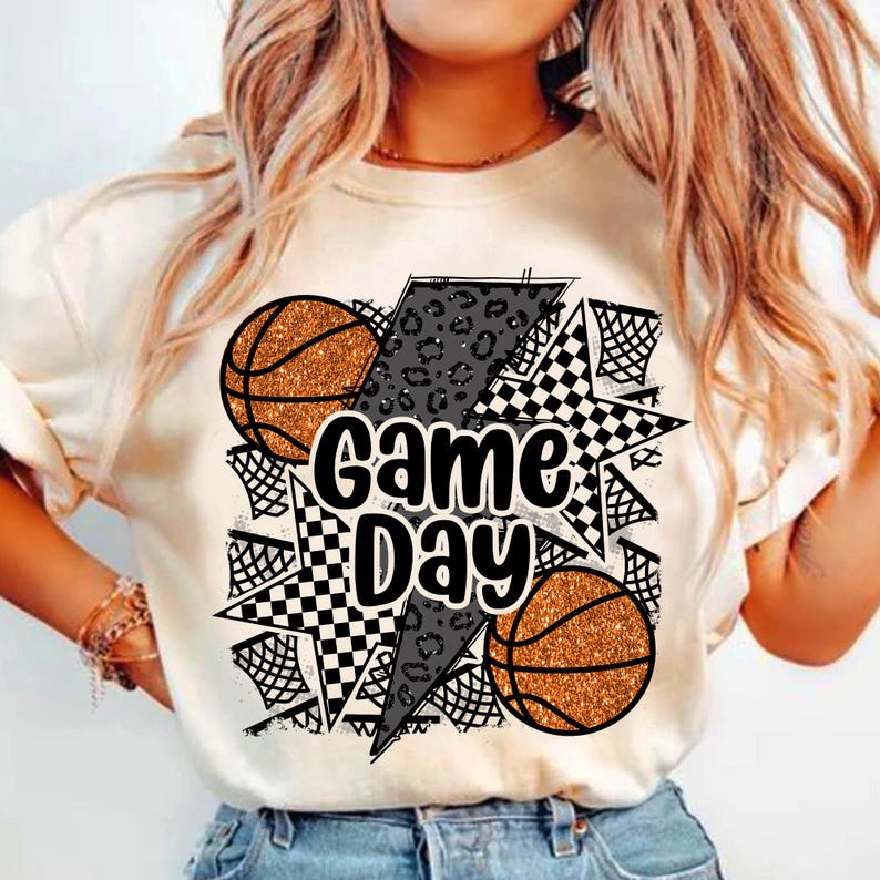 May include: White t-shirt with a graphic design featuring basketballs, a lightning bolt, a chequered star, and the text "Game Day".