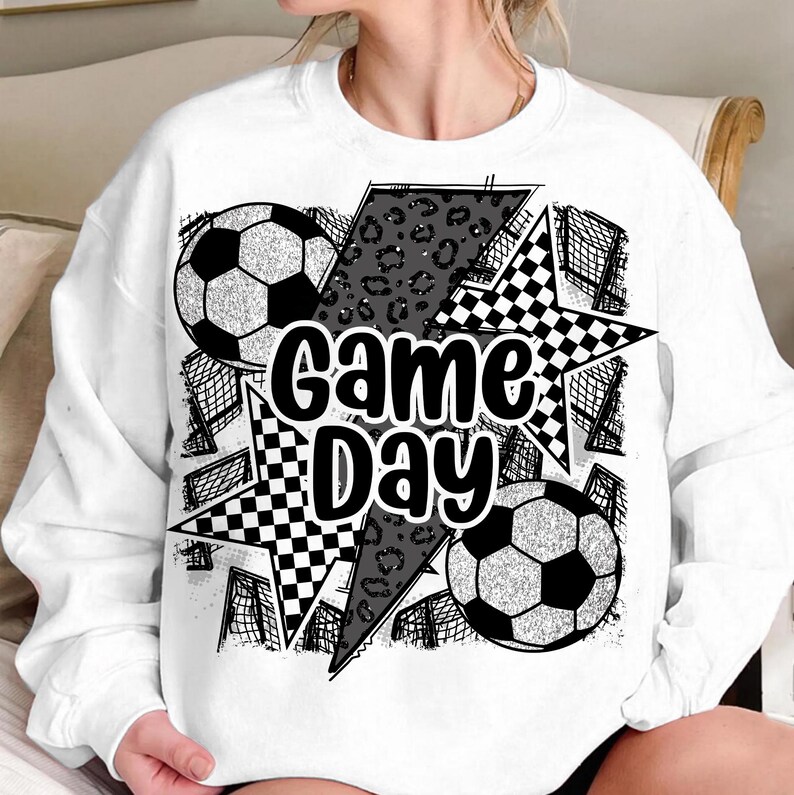 May include: White sweatshirt with a black and white graphic design featuring soccer balls, a star, and the text "Game Day".