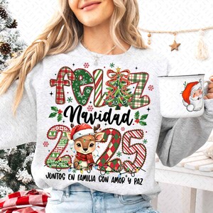 以下が含まれることがあります： お祝いのクリスマスデザインが施されたライトグレーのスウェットシャツ。デザインには、赤と緑のチェック柄の文字で「Feliz Navidad」、クリスマスツリー、サンタ帽をかぶったトナカイが含まれています。サンタクロースのイラストが描かれた白いマグカップも表示されています。