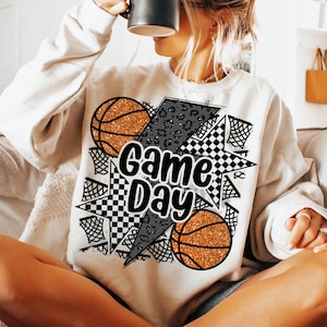 May include: White sweatshirt with a black and white graphic design featuring basketballs, a lightning bolt, and the text "Game Day".