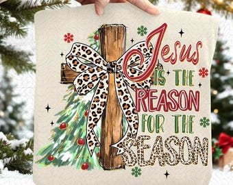 May include: A cream-colored Christmas pillow featuring a wooden cross with a leopard print bow. A green Christmas tree and the text "Jesus is the reason for the season" are also displayed on the pillow.