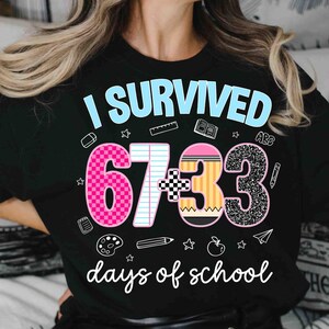 May include: Black t-shirt with the text "I Survived 67+33 days of school." The design includes a pink number 6, a white number 7, a pencil, and a glittery number 3. School-themed graphics surround the text.