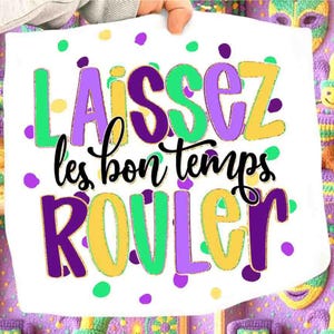 May include: White fabric with the phrase "Laissez les bon temps rouler" in green, purple, and yellow. The text is surrounded by colorful polka dots. The fabric is held up by a person.