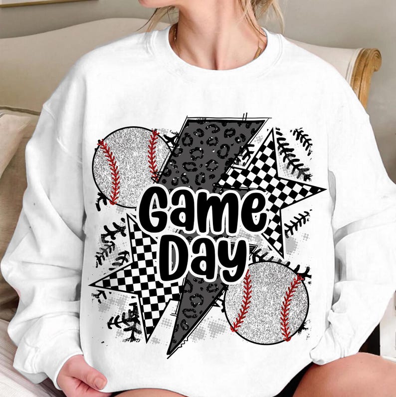 May include: White sweatshirt with a black and white graphic design featuring baseballs, stars, and the text "Game Day".