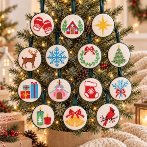 May include: A collection of fourteen round cross-stitch ornaments hanging on a Christmas tree. Each ornament features a unique embroidered design including mittens, a house, a star, a reindeer, a snowflake, a wreath, a tree, gifts, a church, a stocking, pine branches, candles, bells, and a cardinal bird.