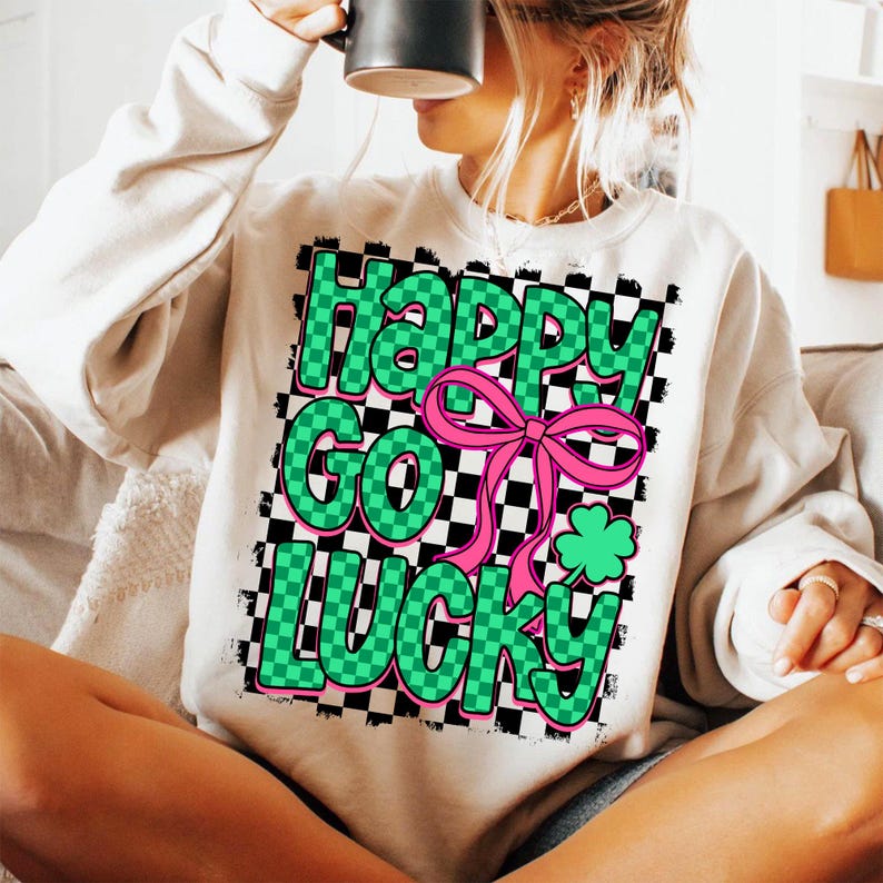 May include: White sweatshirt with a checkered pattern in black and green. The text "Happy Go Lucky" is written in green letters with a pink bow and a green shamrock.