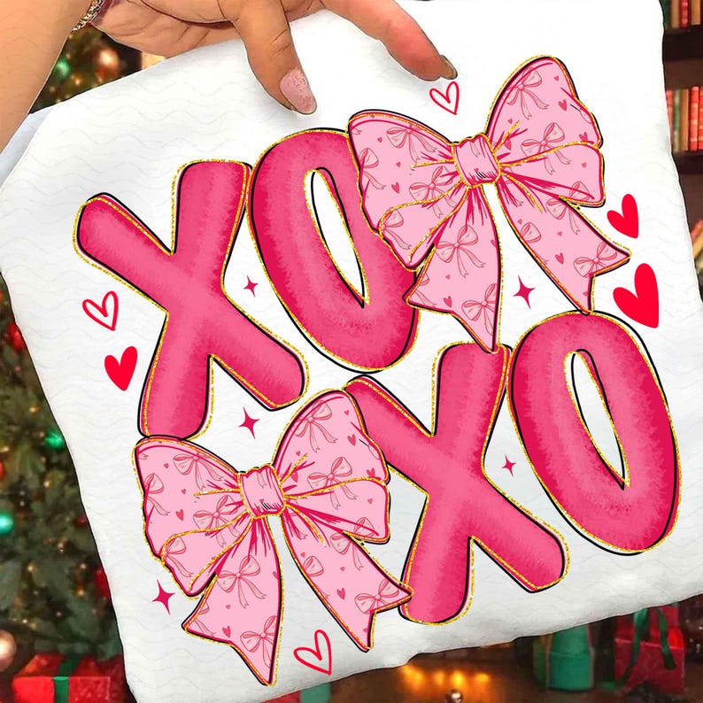 May include: White fabric with a pink "XOXO" design. The letters are outlined in gold and feature pink bows with gold trim. Red hearts and stars are scattered around the letters, creating a romantic theme.