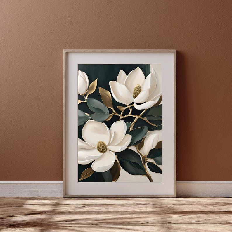 K&ouml;nnte beinhalten: Gerahmter Kunstdruck mit einer botanischen Illustration wei&szlig;er Magnolienbl&uuml;ten mit goldenen Akzenten und dunkelgr&uuml;nen Bl&auml;ttern. Das Kunstwerk ist vor einem dunklen Hintergrund platziert, was einen auff&auml;lligen Kontrast erzeugt. Der Rahmen hat eine helle Holzfarbe.